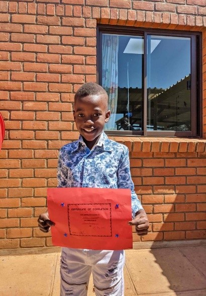 Pictured here is Nathan, an 8-year-old from Malawi who recently concluded his fifth and final round of cancer treatments at one of our supported facilities, holding his chemotherapy completion certificate.