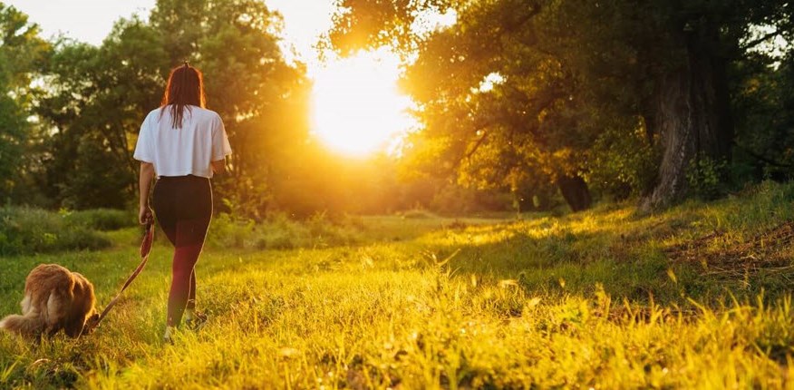 Woman with asthma walking her dog and practicing mindfulness in an open field. 