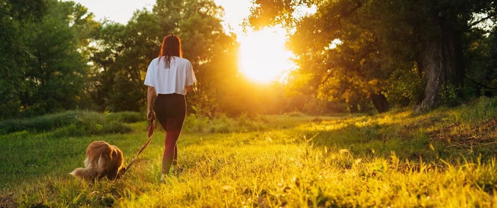 Woman with asthma walking her dog and practicing mindfulness in an open field. 