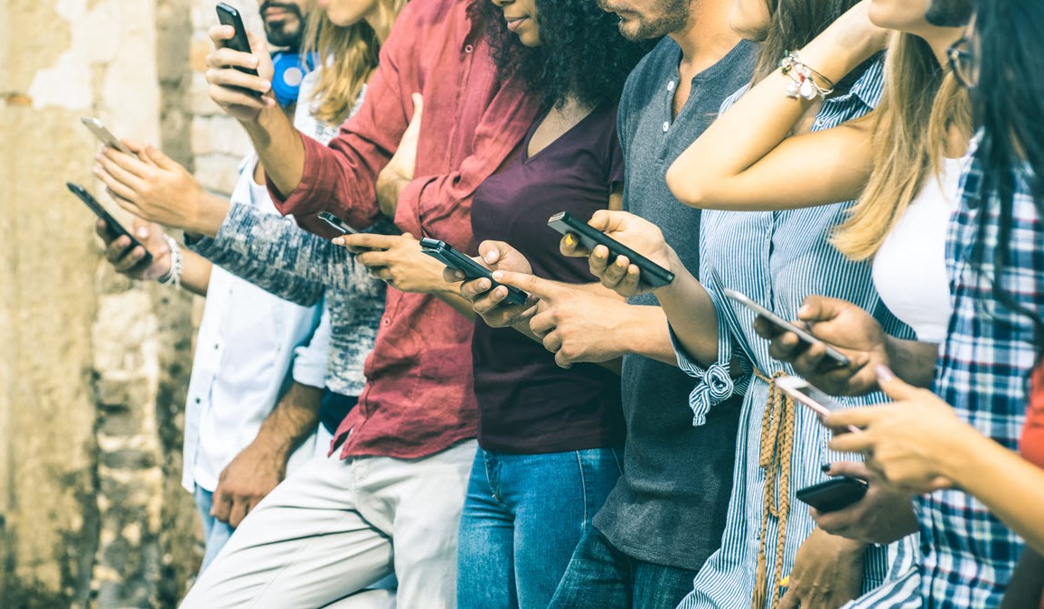 A group of friends check their phones in a line