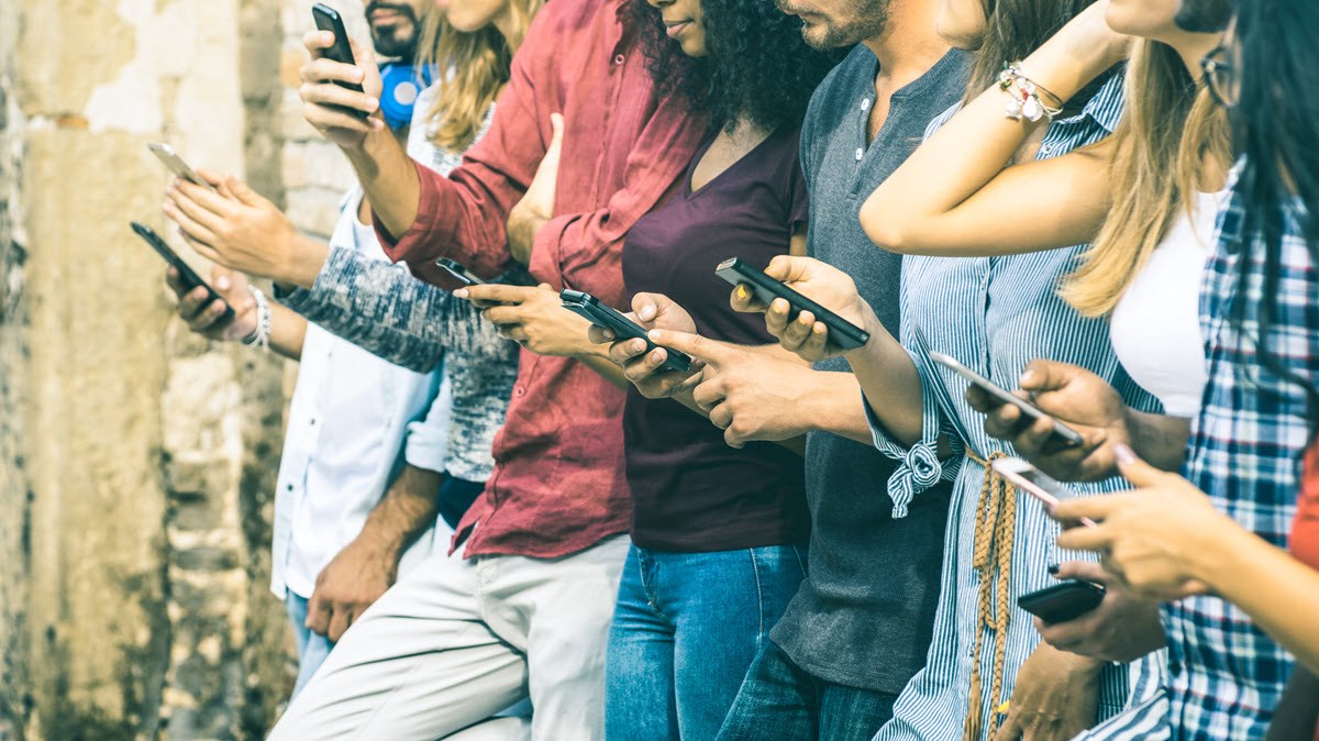 A group of friends check their phones in a line