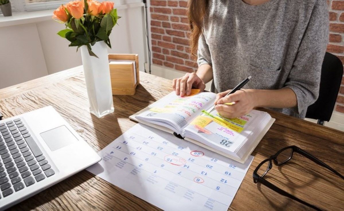 A woman with ADHD keeping track of appointments and deadlines in calendar diary