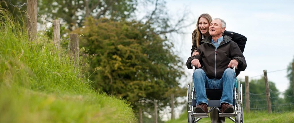 Caregiver and loved one in wheelchair happily living in the moment as they go for a walk