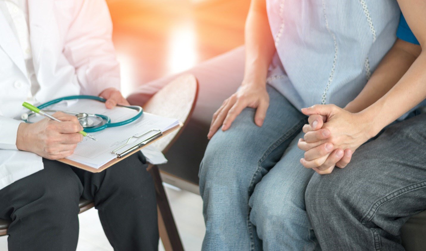 Couple hold hands as they consult an IVF clinician