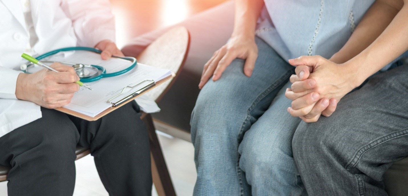 Couple hold hands as they consult an IVF clinician