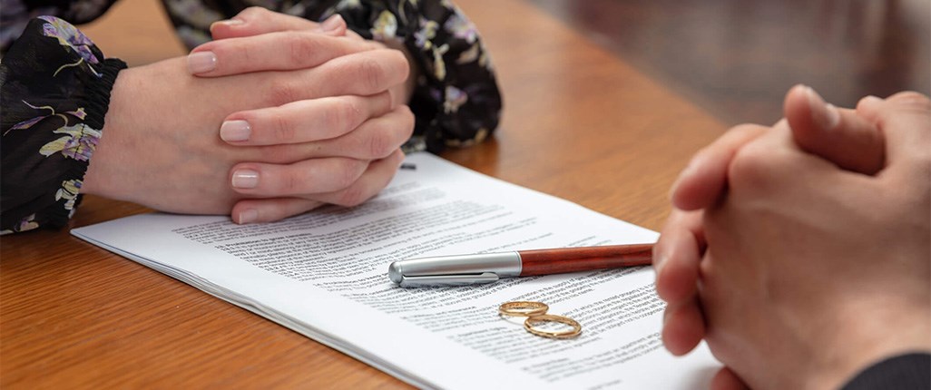 Couple discussing divorce with papers and rings on table 