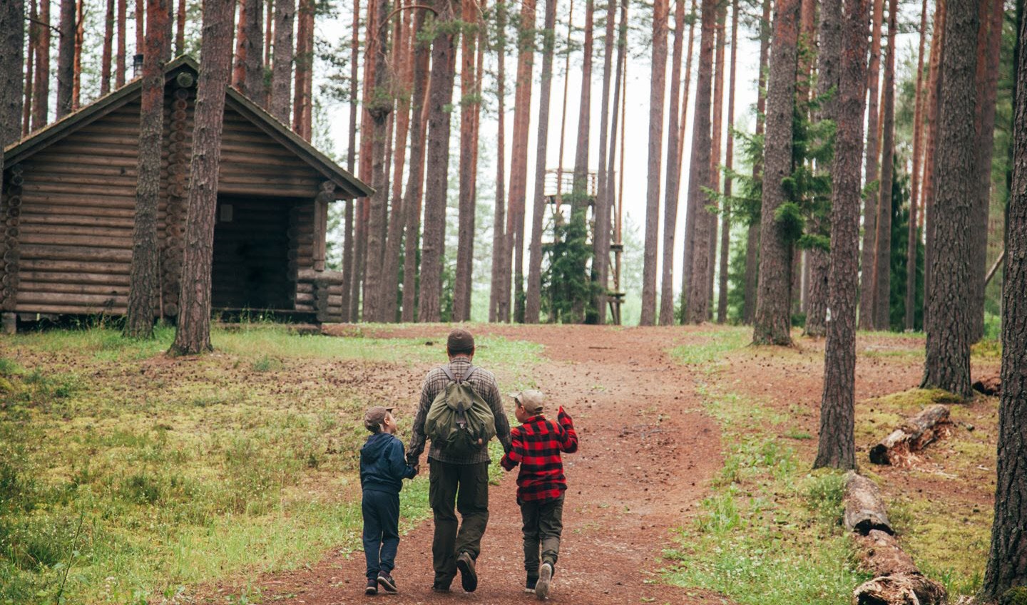 Dad holds hands with children as they walk in the woods