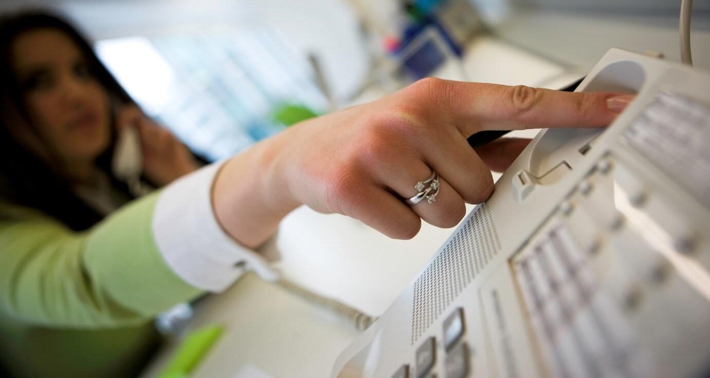 Woman hangs up her office landline due to anxiety during a call. 