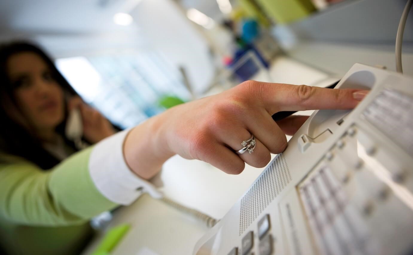 Woman hangs up her office landline due to anxiety during a call. 