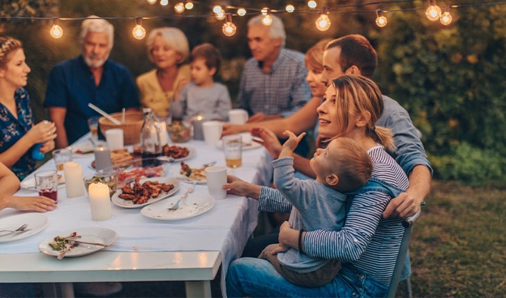 Family having a dinner in the yard under the lights