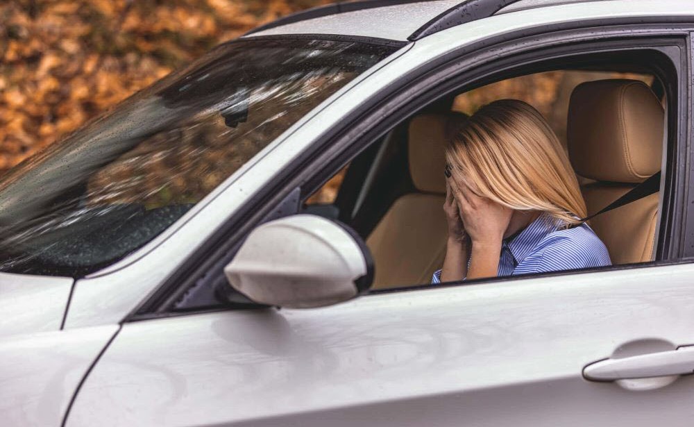 Female caregiver sitting in car letting herself cry and feel upset