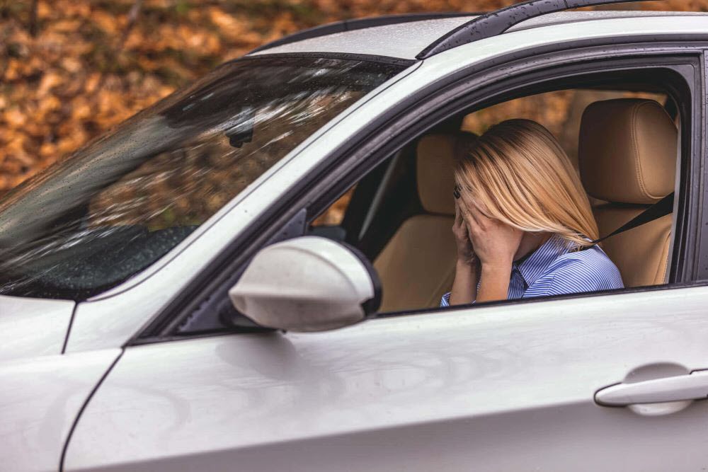 Female caregiver sitting in car letting herself cry and feel upset