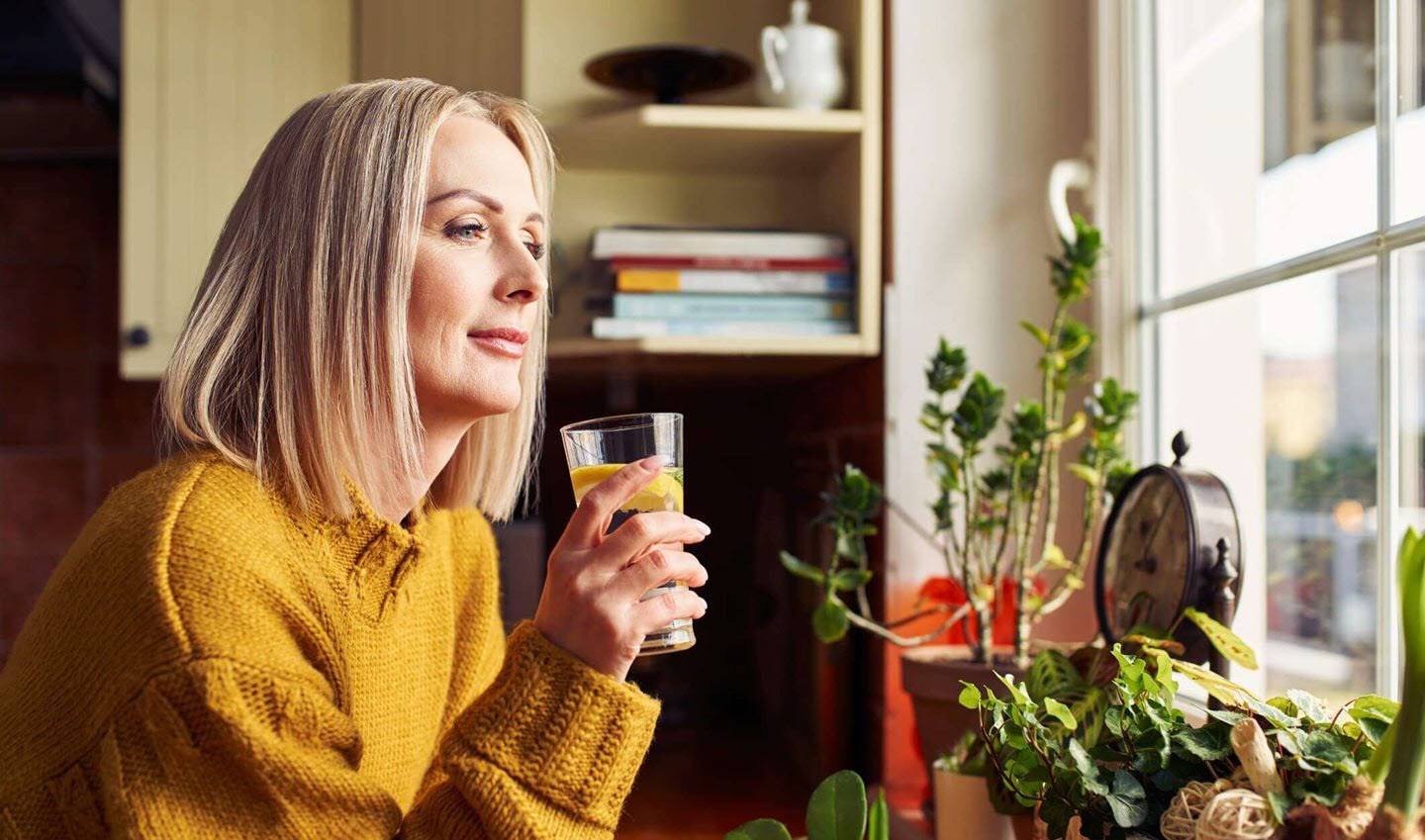 Female heart patient, drinking water, confidently reflecting on new, healthy choices