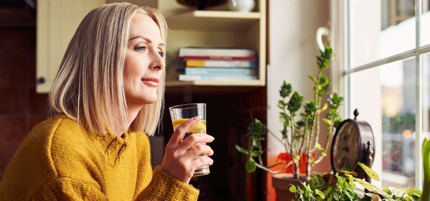 Female heart patient, drinking water, confidently reflecting on new, healthy choices