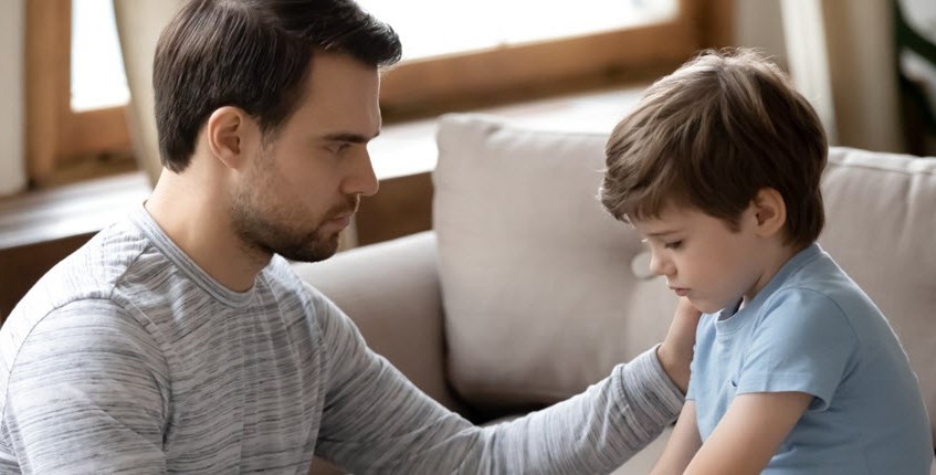 Young caregiver comforts his little brother in the living room