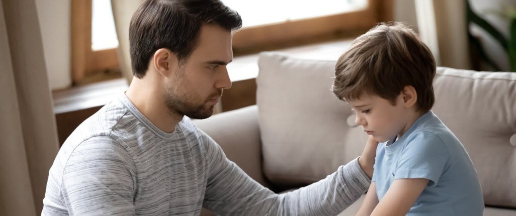 Young caregiver comforts his little brother in the living room