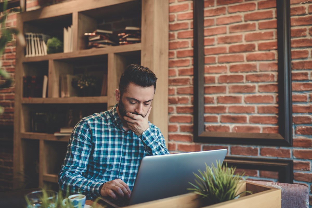 Man reading about world news on his laptop, feeling depressed and hopeless