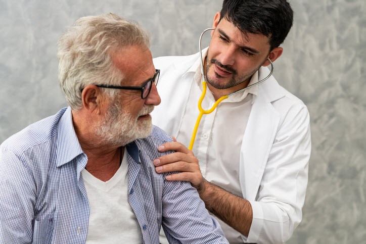 Respiratory therapist checking the lungs of a senior male patient with asthma