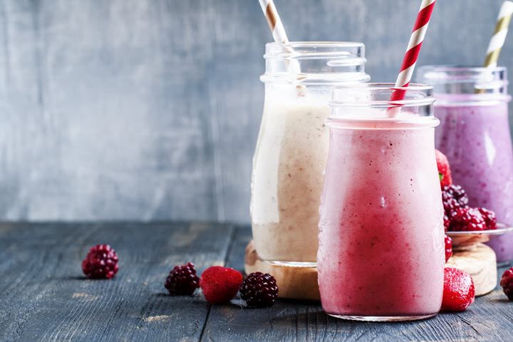 Three migraine-friendly fruit smoothies with a scattering of berries