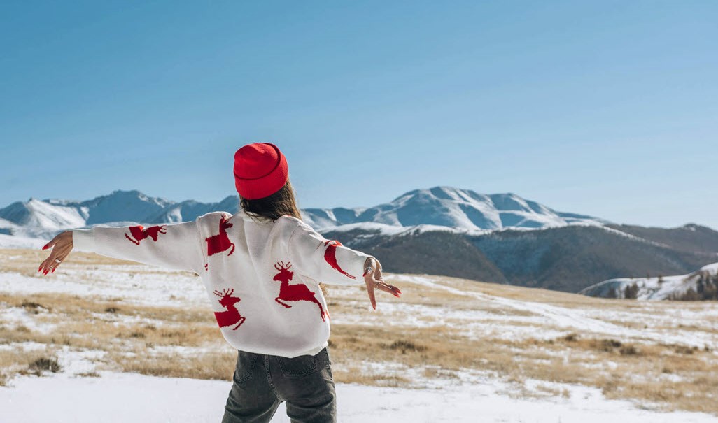 Woman in Christmas jumper and hat enjoying being away for the holidays anxiety-free