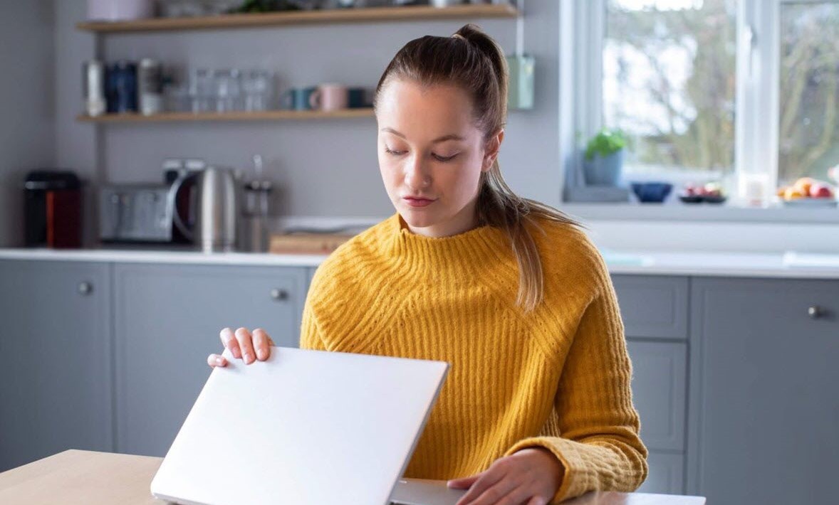 Woman concerned about triggering cancer awareness month content on social media closing lid of laptop computer