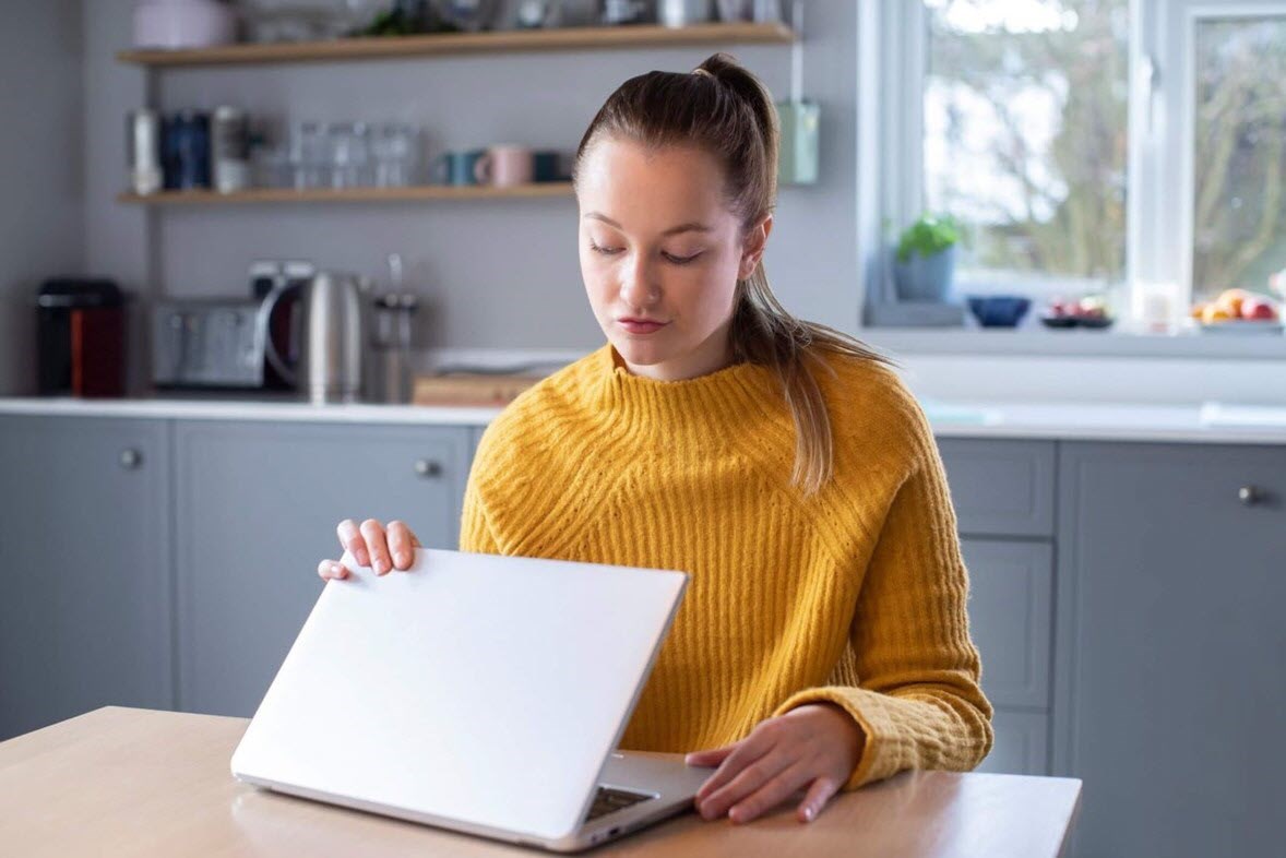 Woman concerned about triggering cancer awareness month content on social media closing lid of laptop computer