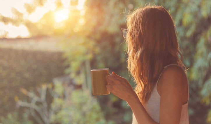 Woman drinking coffee and taking in her garden during self-isolation.