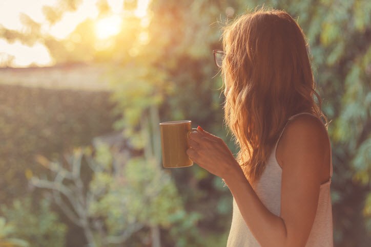 Woman drinking coffee and taking in her garden during self-isolation.