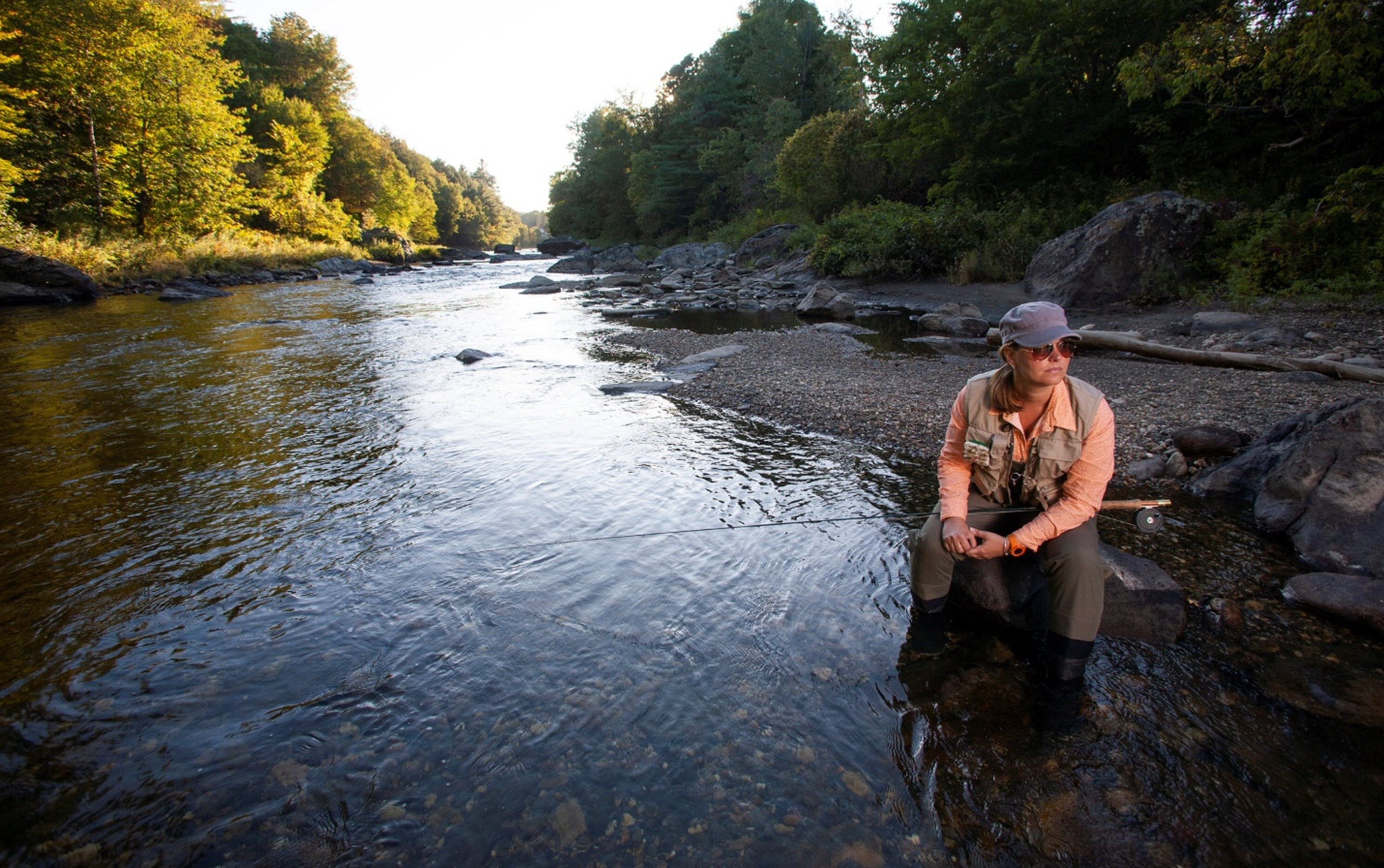 Woman looking thoughtful as she fishes in mountain river