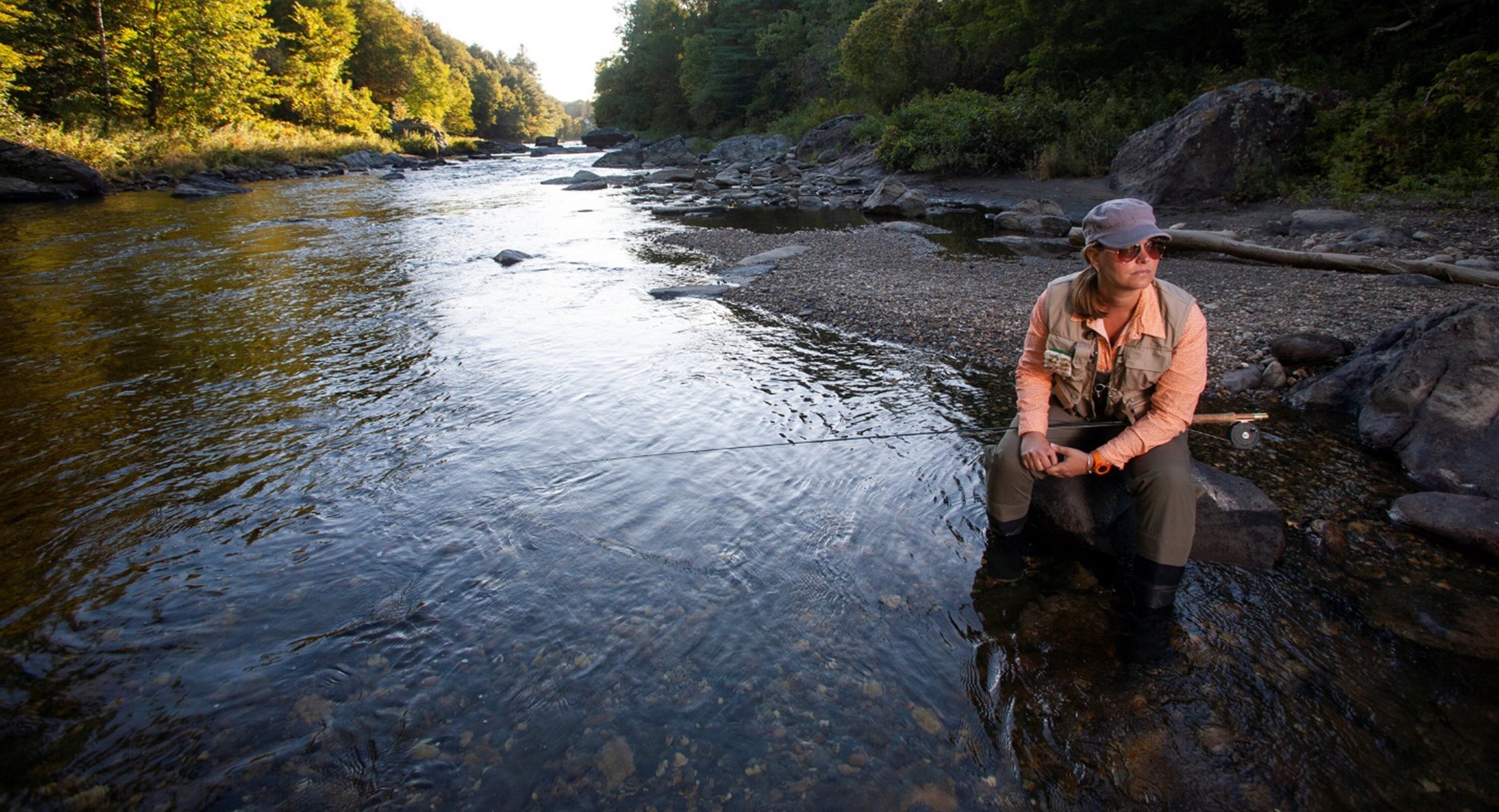 Woman looking thoughtful as she fishes in mountain river