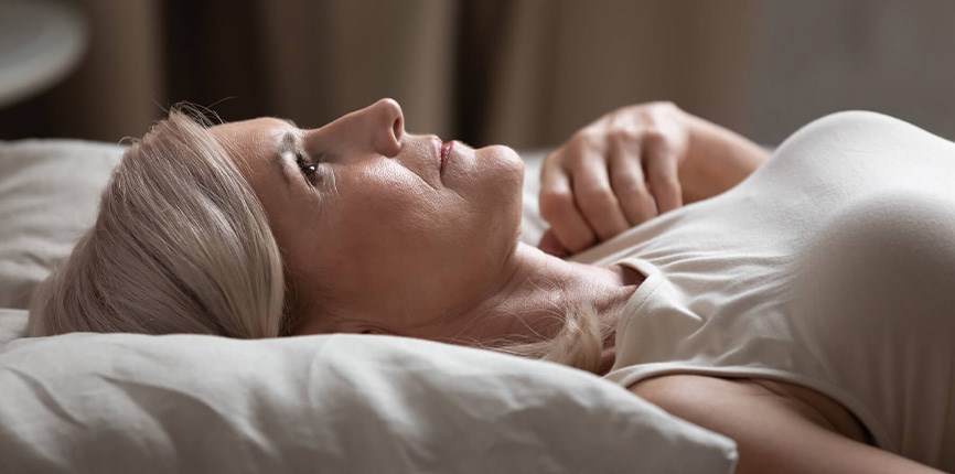 Sleepless woman lying in bed worried about caregiving responsibilities