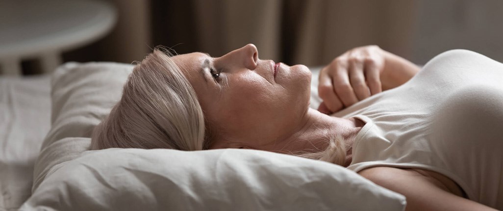 Sleepless woman lying in bed worried about caregiving responsibilities