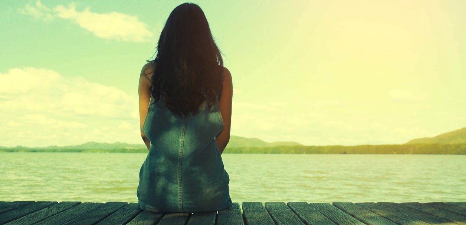 Woman reflecting on mental health troubles as she looks out to sea