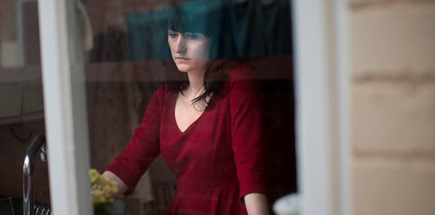 Woman staring out of window ruminating on imagined mistakes