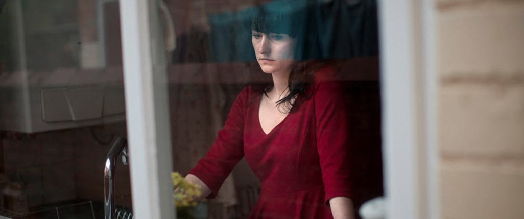 Woman staring out of window ruminating on imagined mistakes