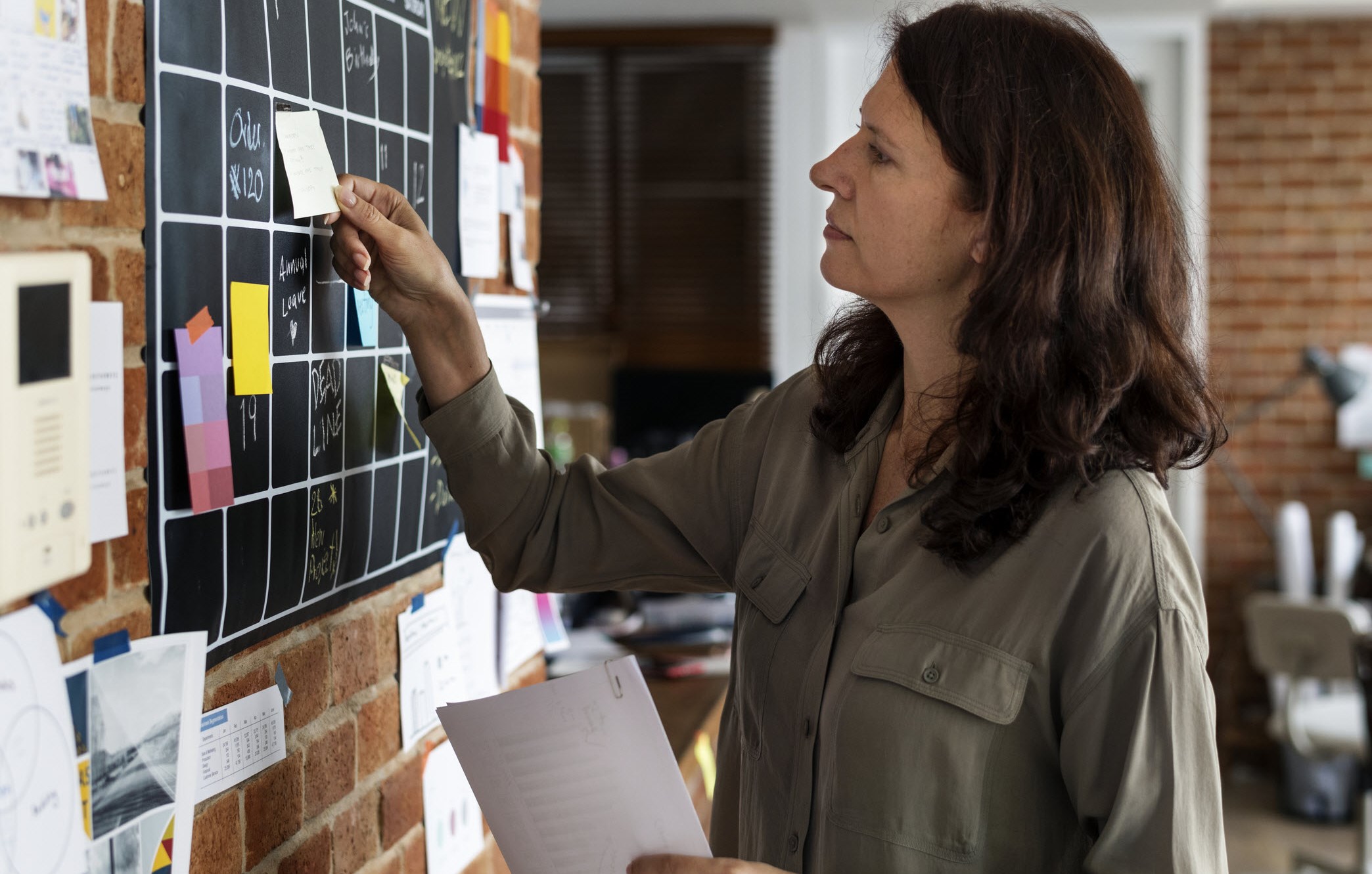 Woman with ADHD using a wall chart calendar and sticky notes to track daily tasks