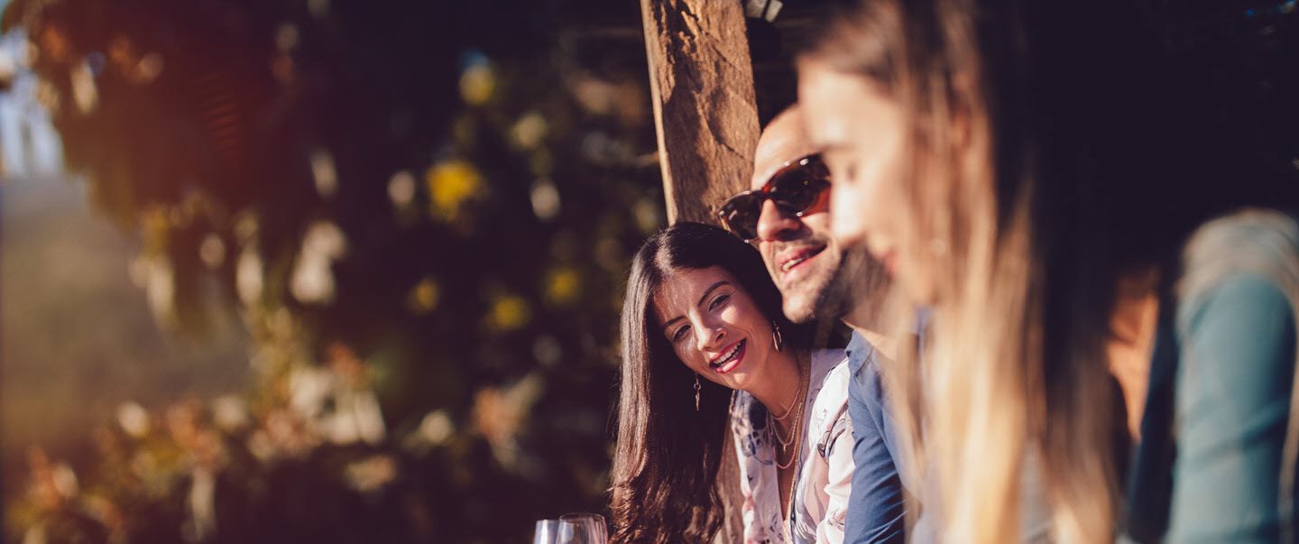 Woman with asthma drinking red wine with friends outside as the sun sets.