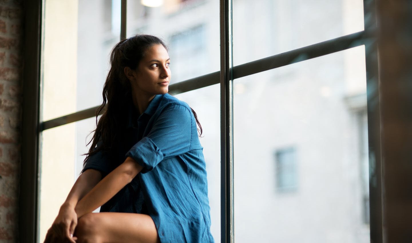 Woman with asthma looking out of window pensively.