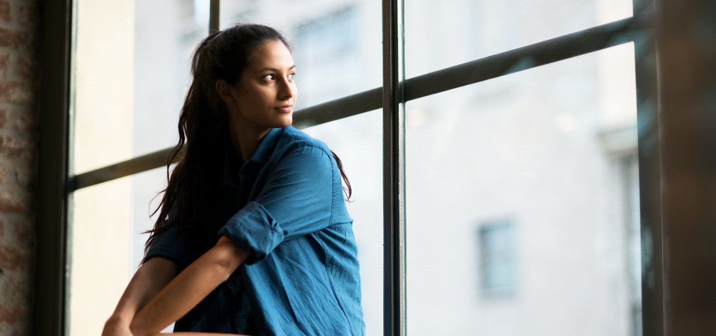 Woman with asthma looking out of window pensively.