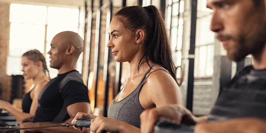 Woman with asthma enjoying cardio workout class on rowing machine