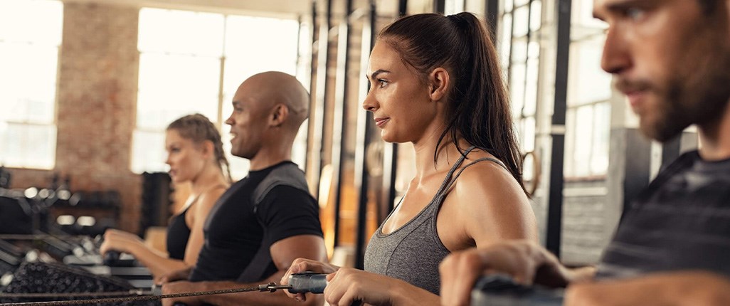 Woman with asthma enjoying cardio workout class on rowing machine