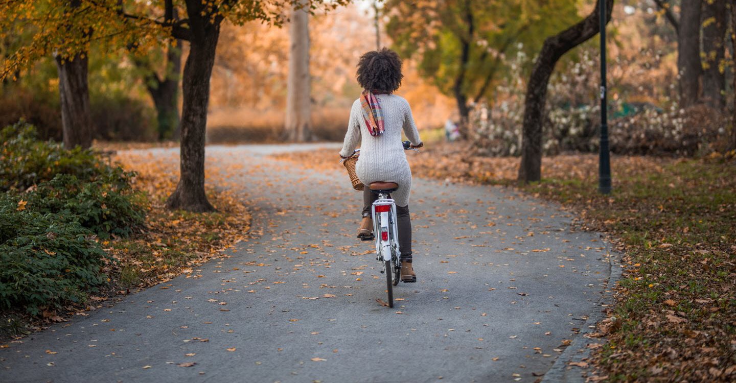 Woman with asthma riding a bike on an autumn road.