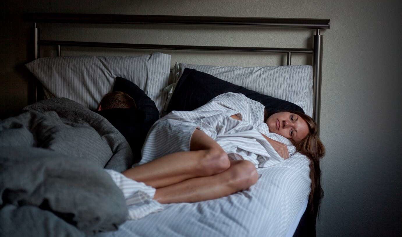 Woman with insomnia and sleep issues anxiously awake in bed