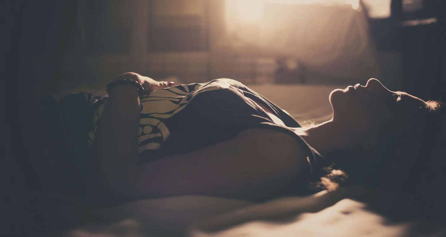 Woman with migraine laying in a darkened room