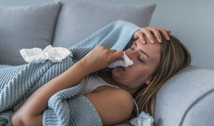 Woman with stuffed nose laying on sofa