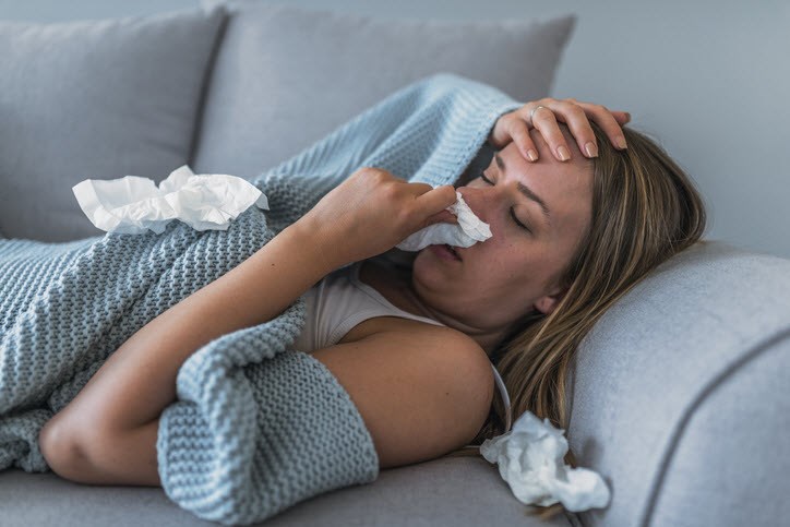 Woman with stuffed nose laying on sofa