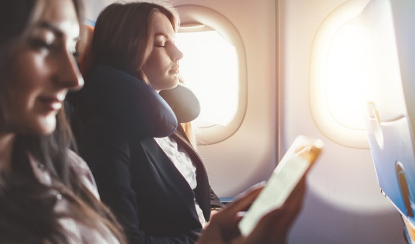 Young woman on plane using meditation techniques to combat anxiety.