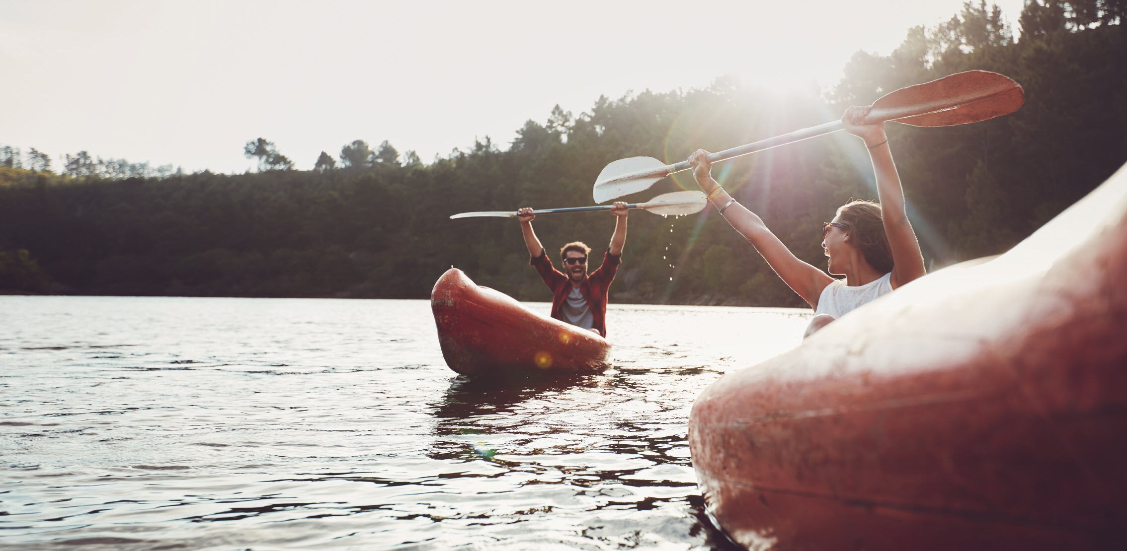 Man kayaking and holding up his paddle in triumph over his new healthier lifestyle during and after cancer treatment