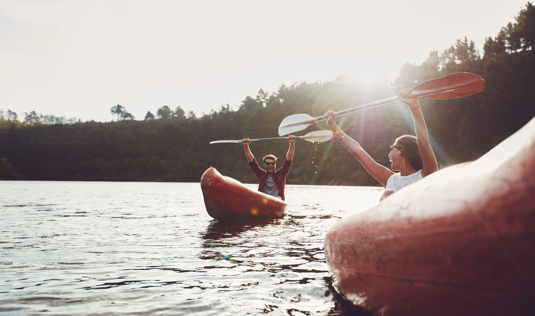 Man kayaking and holding up his paddle in triumph over his new healthier lifestyle during and after cancer treatment