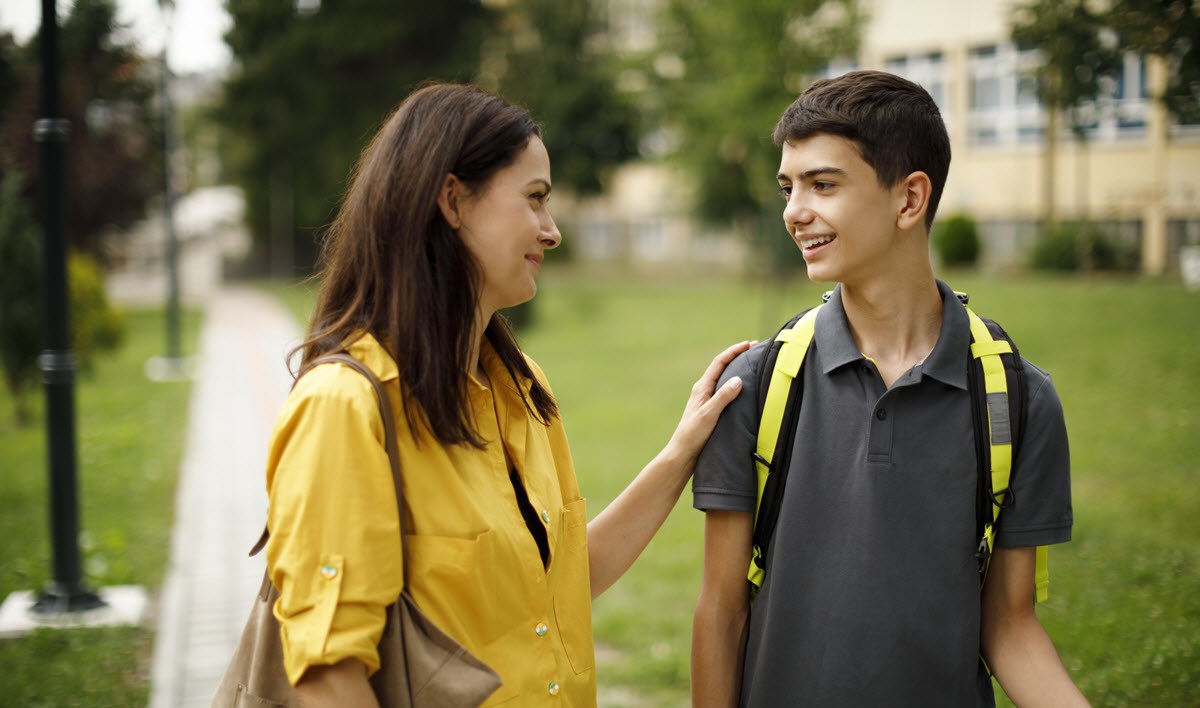 Mom and teenage son having talk about migraine as they walk to school